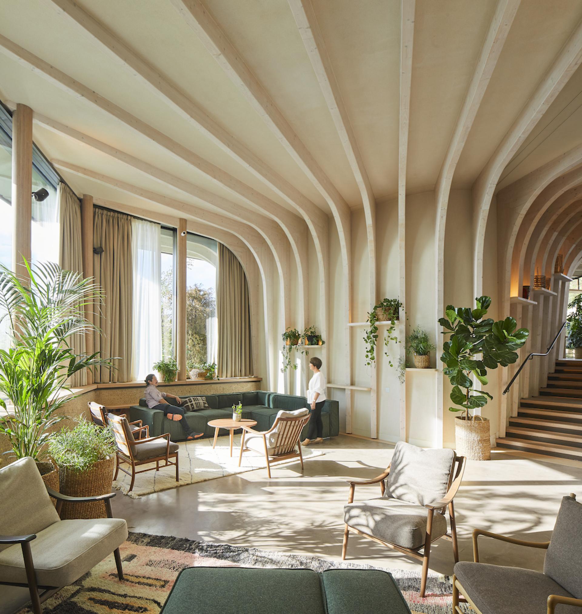 Interior of Maggie's Leeds featuring natural light, stylish seating, and greenery, designed by Heatherwick Studio to promote wellbeing.