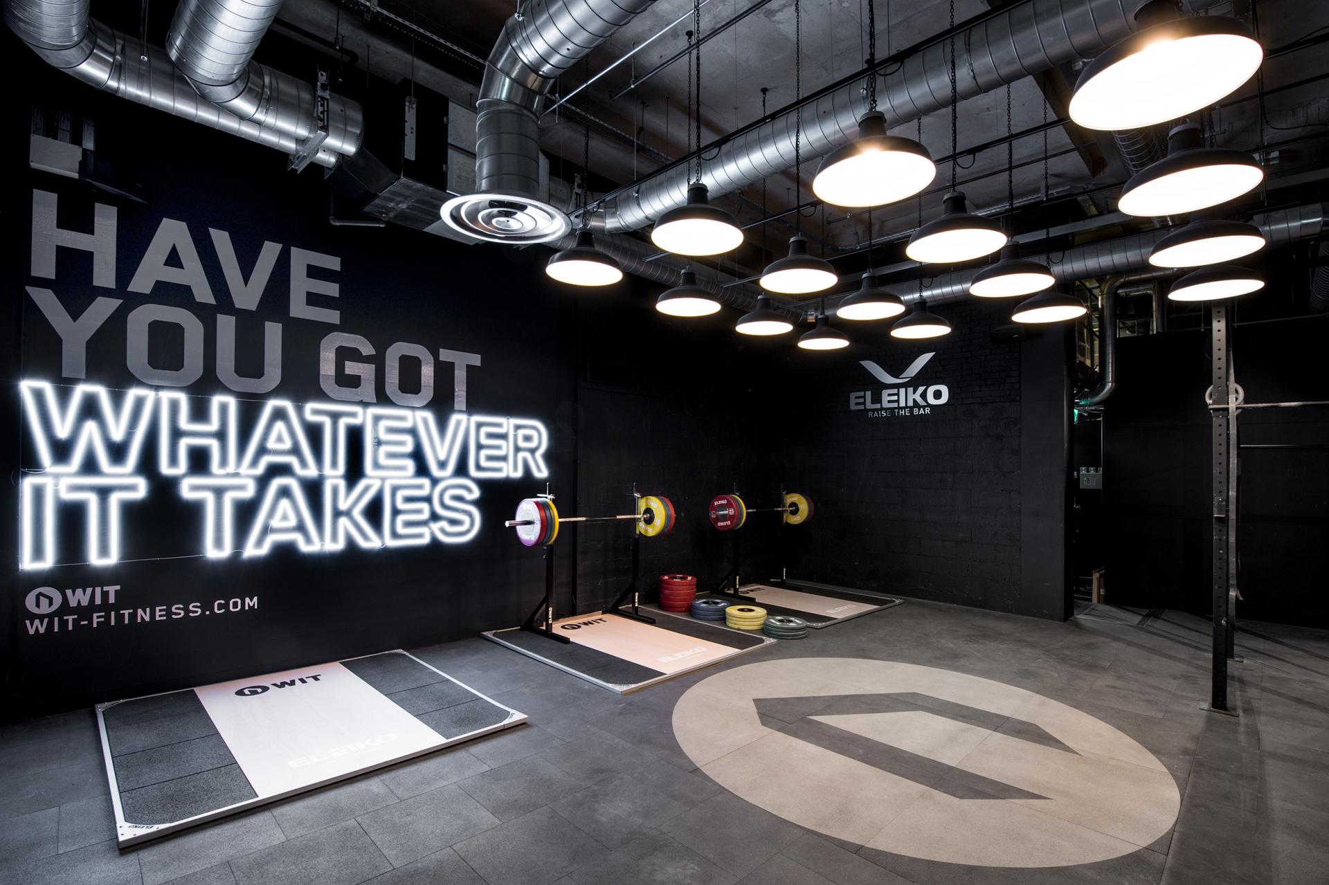 Modern gym interior with weightlifting equipment, motivational signage, and sleek design highlighting fitness and sports performance.