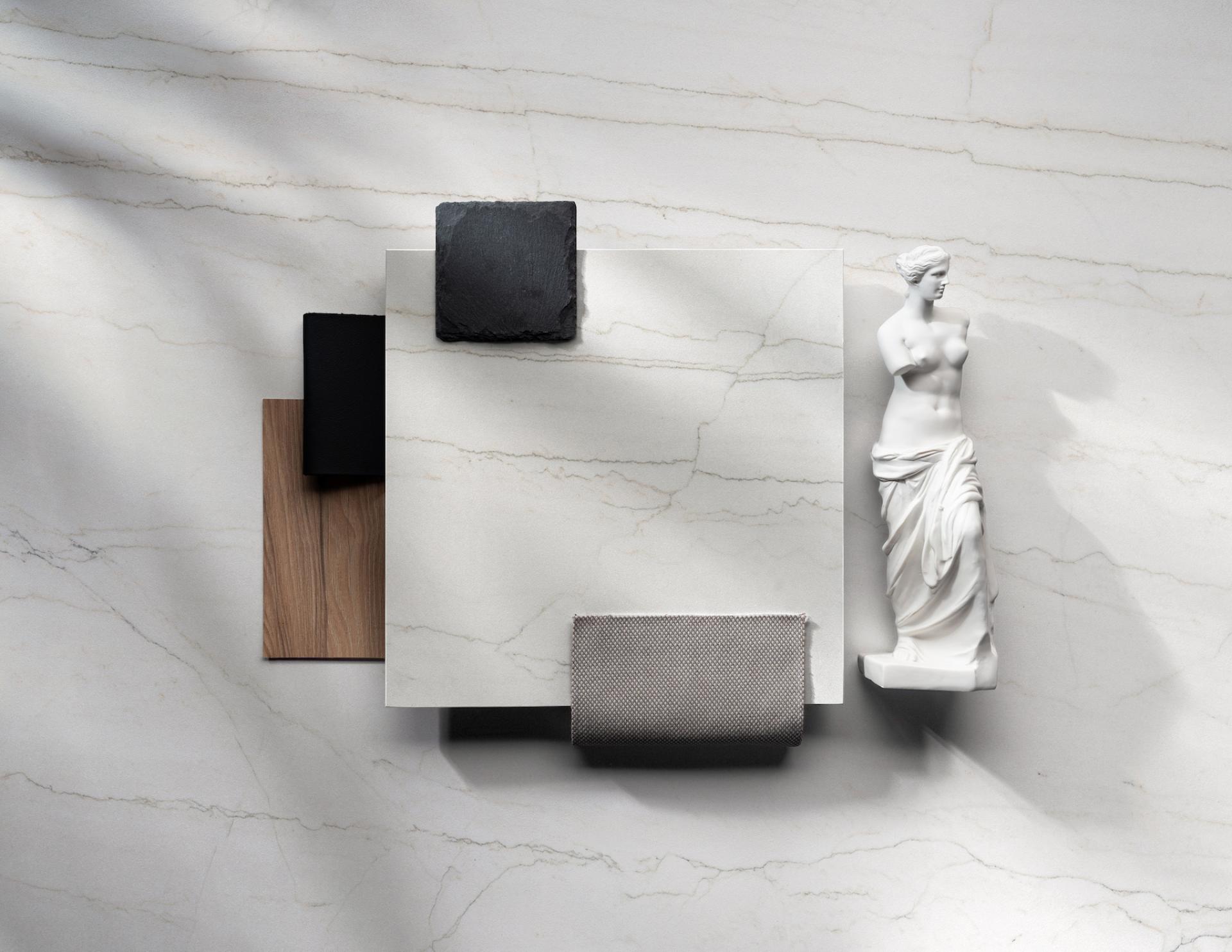 Stylish display of Dekton® materials with a marble surface, showcasing Onirika and Kraftizen collections alongside a sculpture.