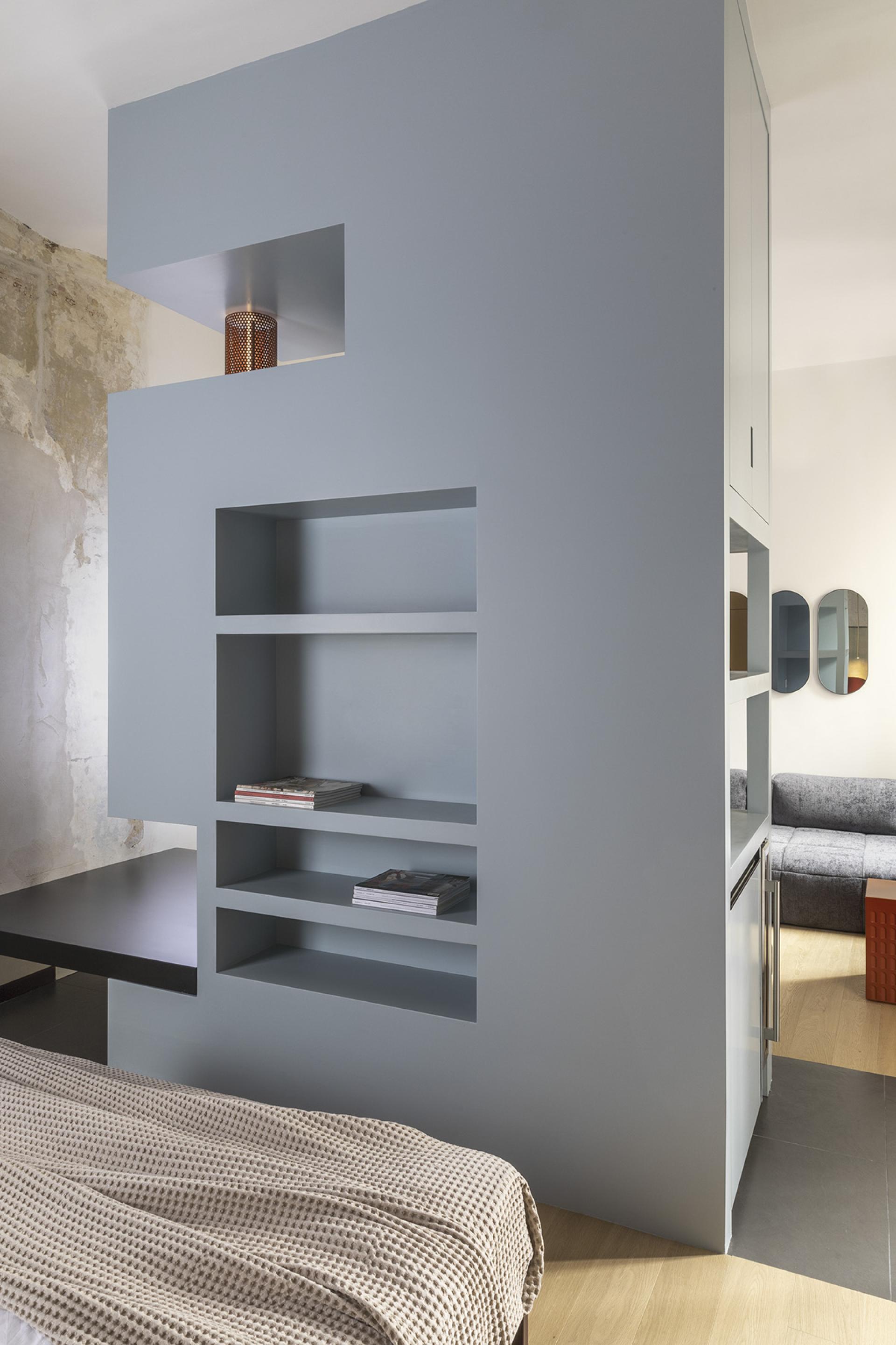 Stylish modern apartment interior in Trastevere, featuring grey partitioning, built-in shelves, and a cozy bed.