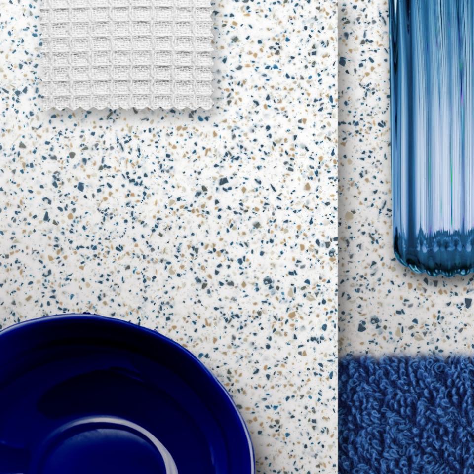 Corian® surface featuring natural-inspired patterns, complemented by textile, blue glass, and ceramic items for design aesthetics.