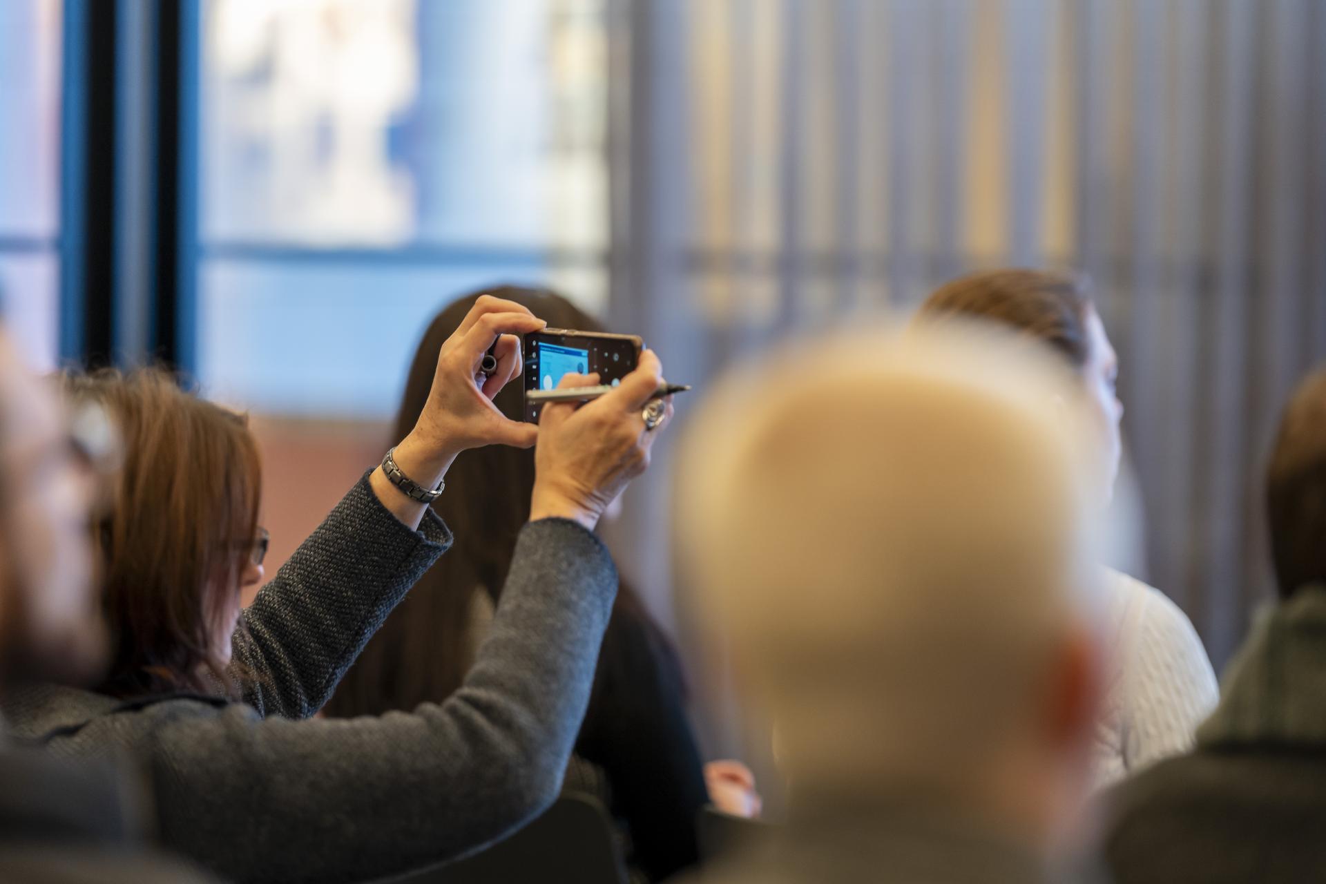 Audience member capturing a moment during a presentation at the Graphene Engineering Innovation Centre event in Manchester.