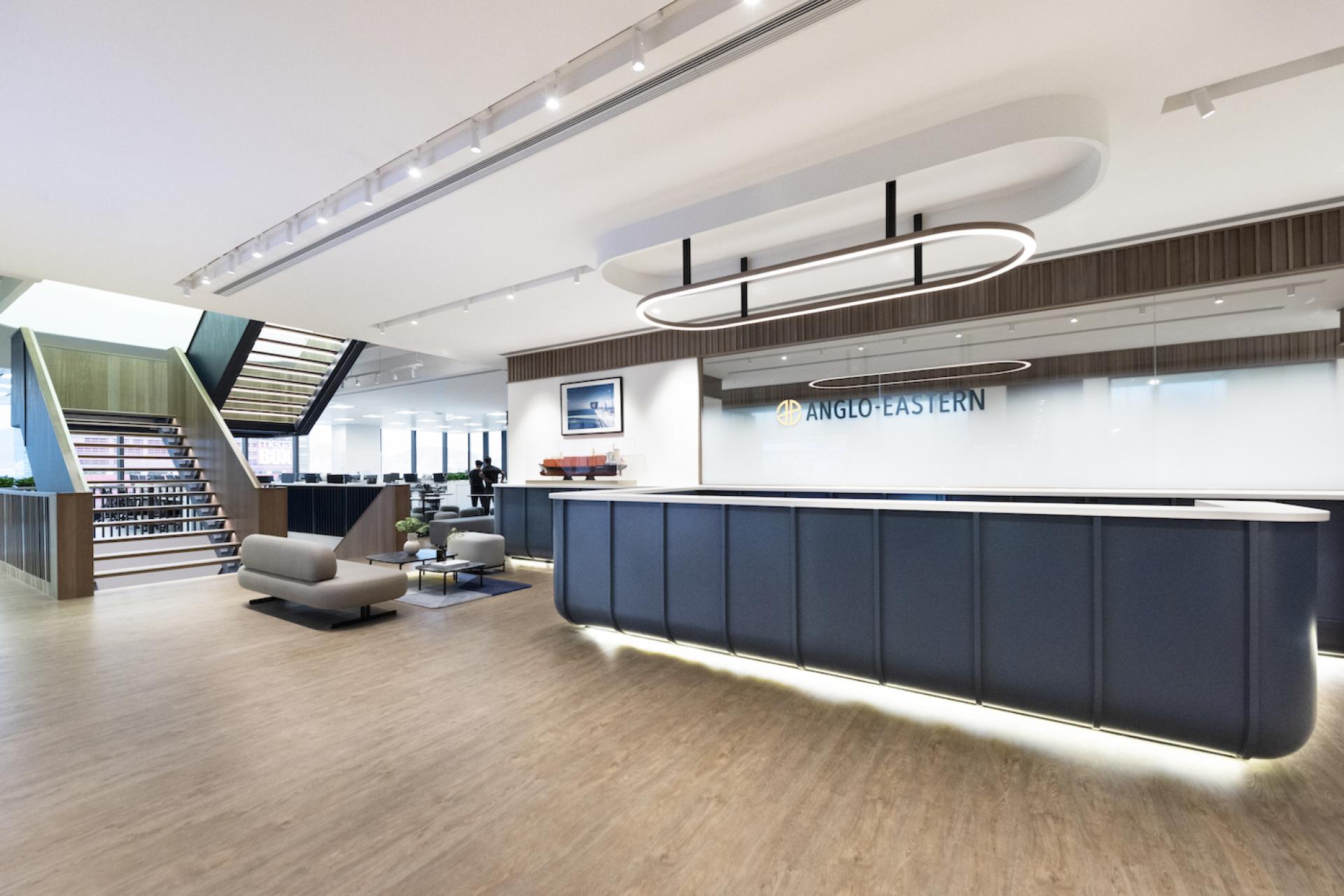 Modern office reception area featuring an internal staircase, stylish furniture, and a prominent reception desk for Bean Buro's headquarters design.