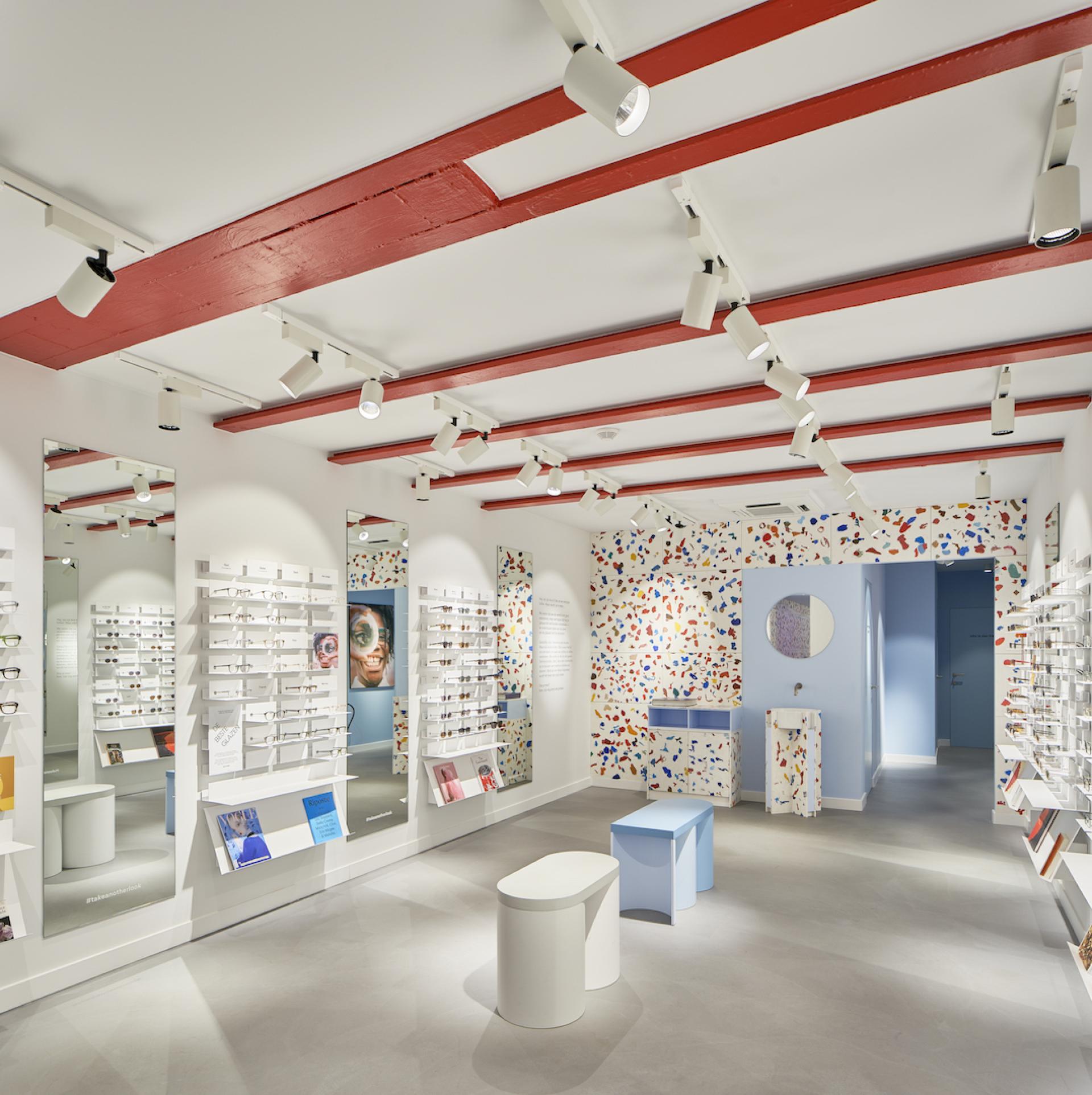 Stylish eyewear store interior featuring a fully recycled design, colorful décor, and mirrors reflecting unique glasses collections.