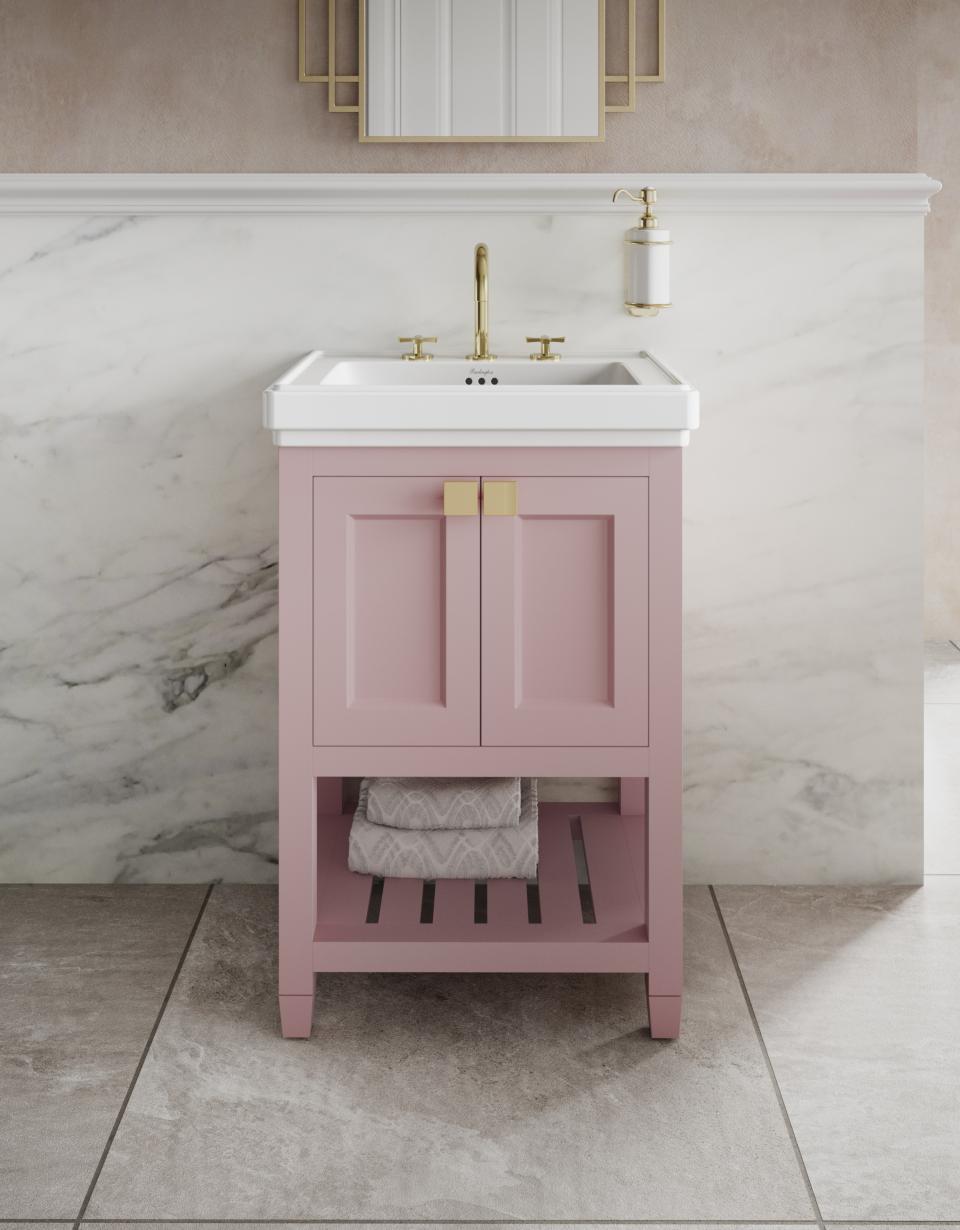 Elegant pink bathroom vanity with white countertop and brass fixtures, set against a marble backdrop, inspired by classic design.