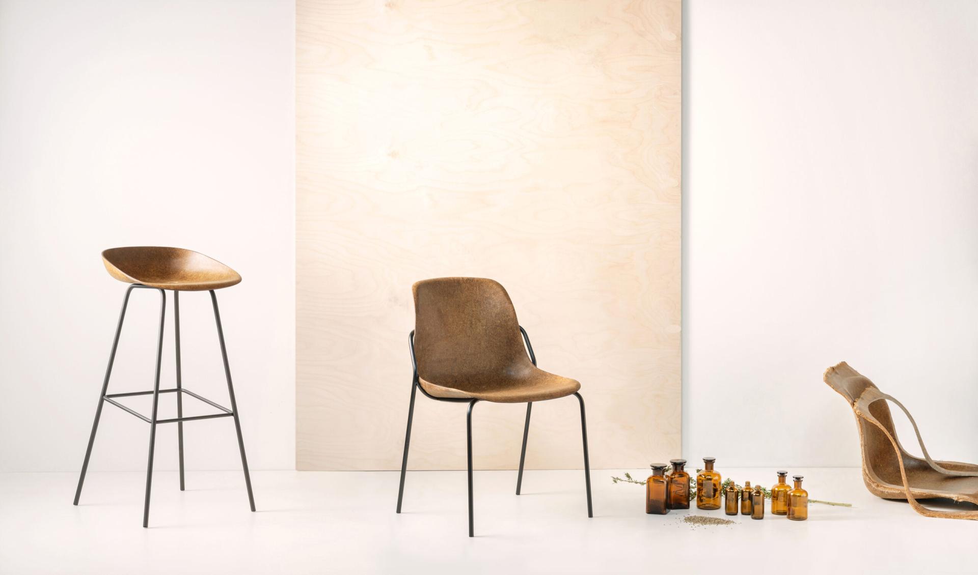 Modern brown chairs and glass bottles arranged against a minimalist backdrop, showcasing sustainable design at Orgatec 2024.