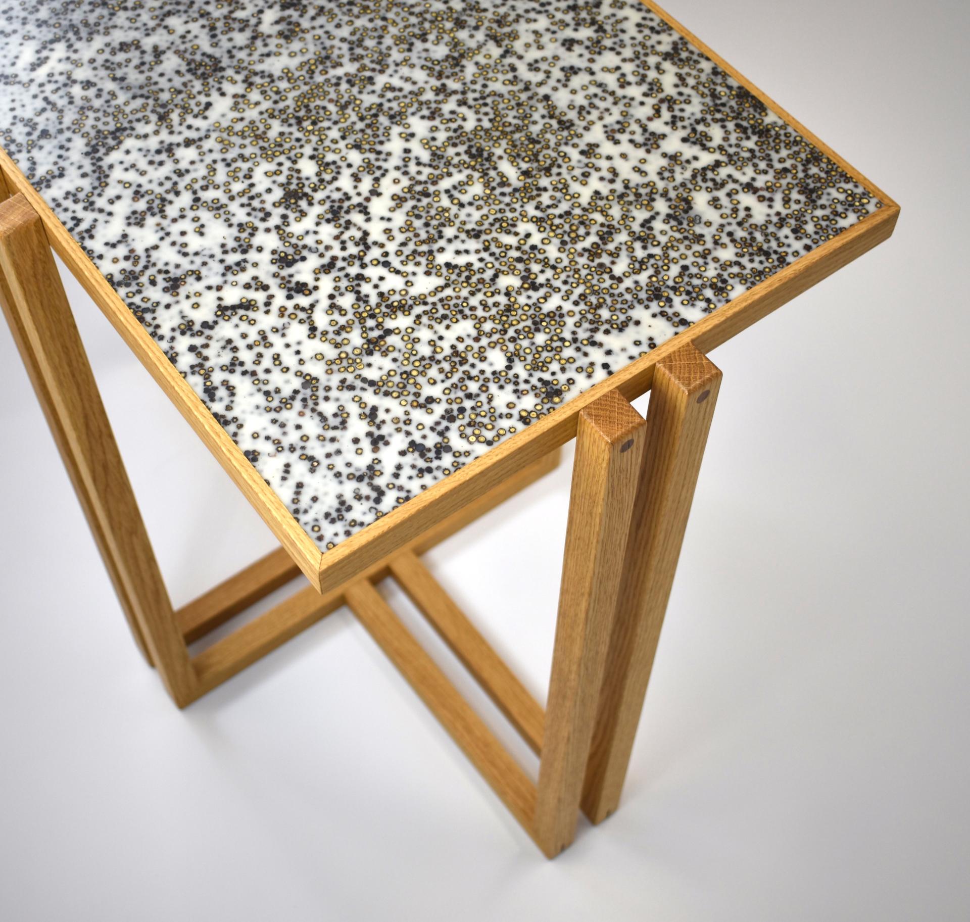 Contemporary wooden table featuring a decorative resin top with textured black and gold beads, designed by Laurent Peacock.