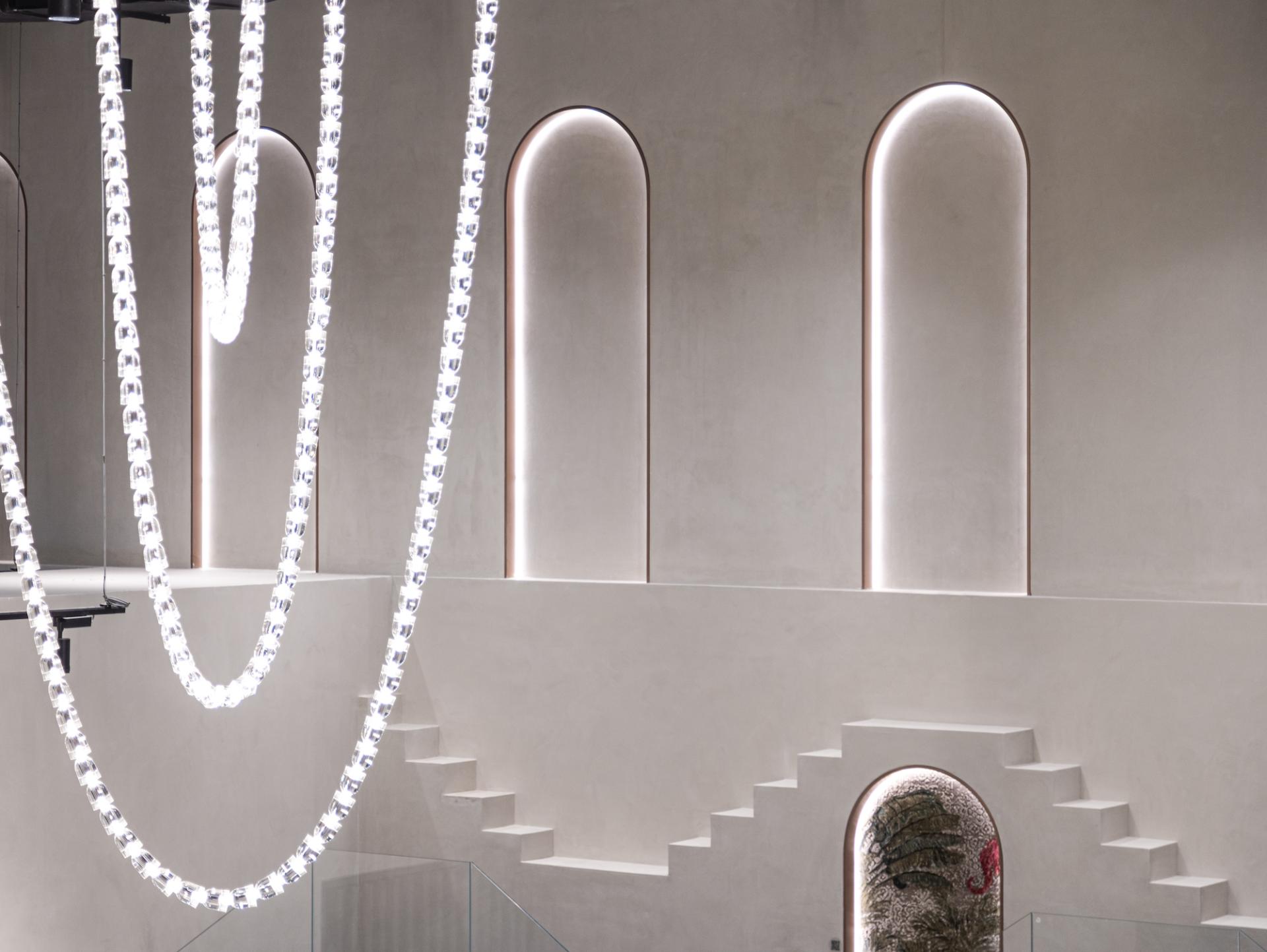 Rajasthani-inspired architecture featuring illuminated arches and a striking rug display in Jaipur Rugs' Dubai showroom.