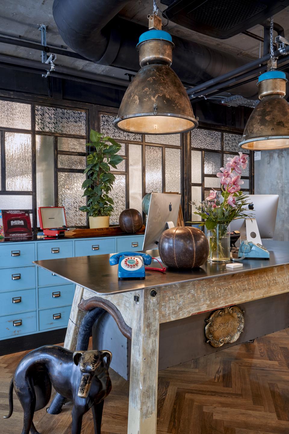 Stylish hotel reception desk featuring vintage decor, blue telephone, plants, and unique artwork in Vienna's Neubau neighborhood.