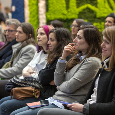 Audience engaged in motivational presentations at the 2020 Surface Design Show in London, surrounded by vibrant greenery.
