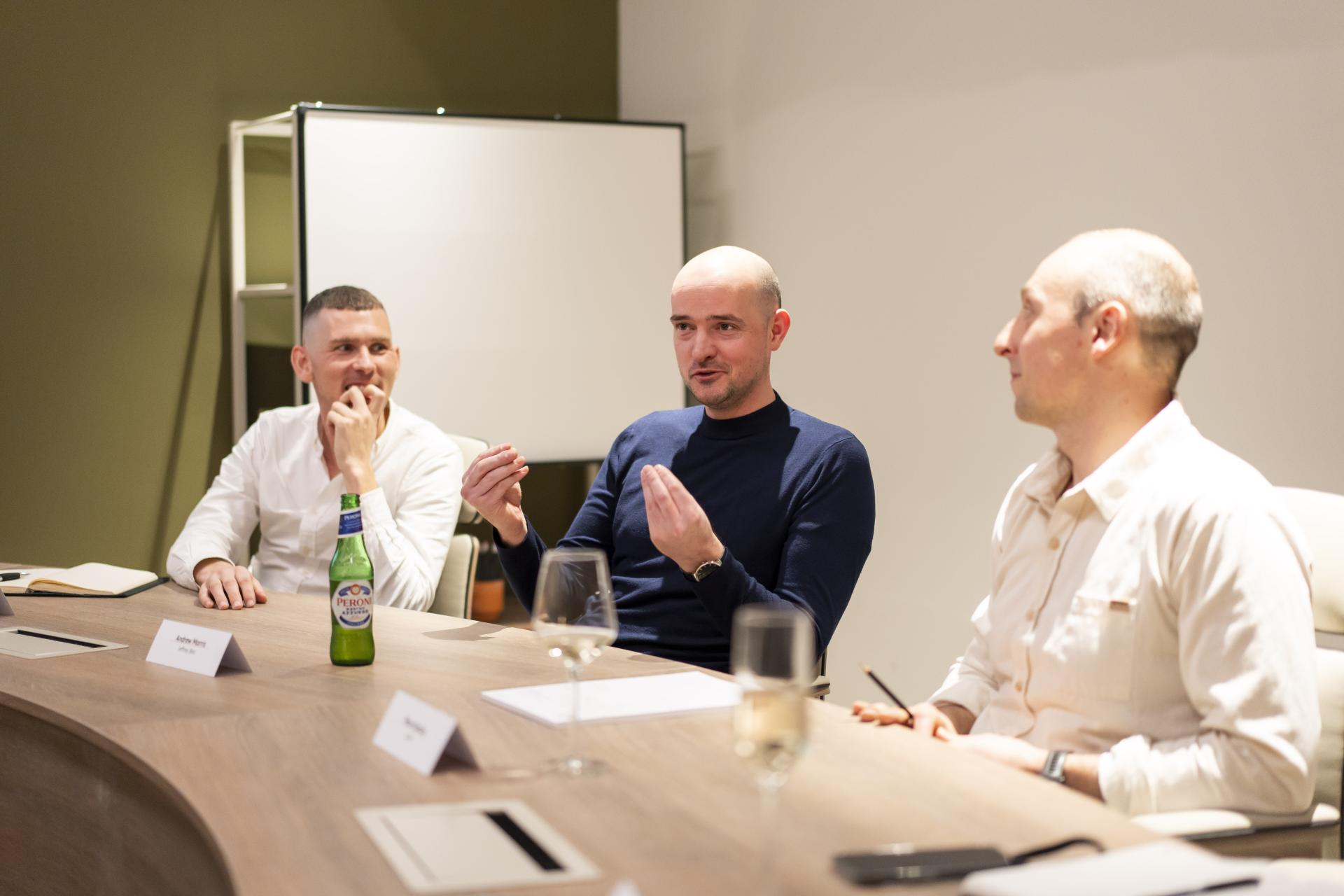 Senior designers engage in discussion about how technology influences sustainability in design during a collaborative meeting.