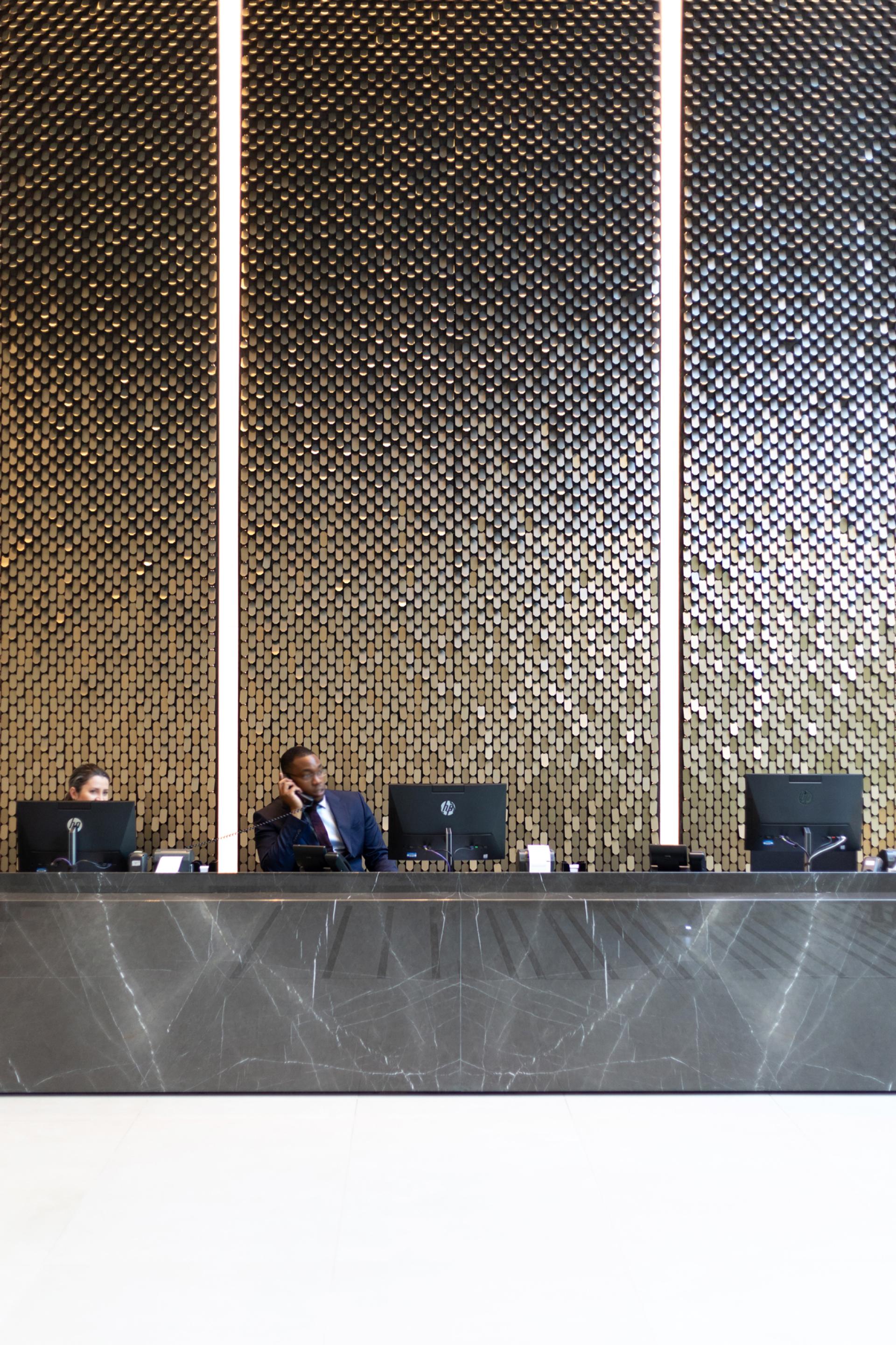Reception area featuring a unique patterned wall, showcasing innovative design by Giles Miller Studio, with staff engaged in their duties.