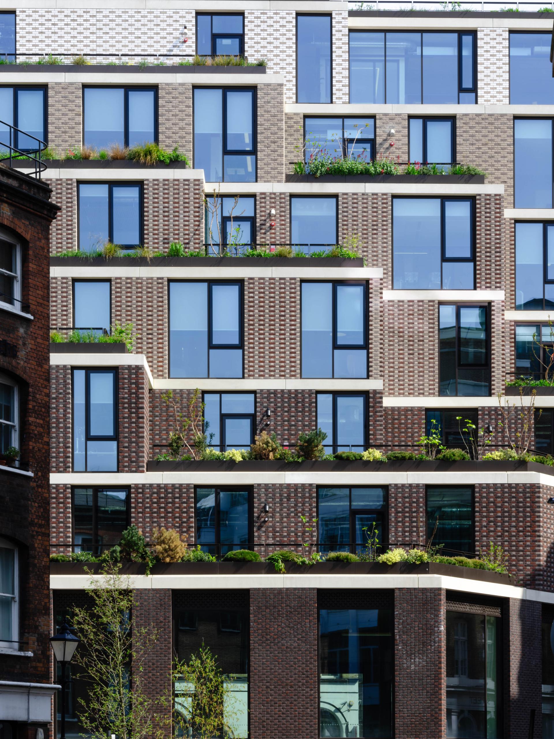 Contemporary brick building design featuring plant-filled terraces, showcasing award-winning architecture from the 2019 Brick Awards.