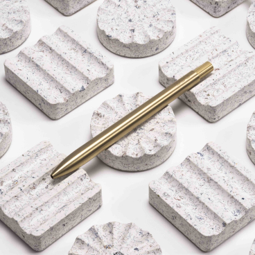 Ebonite terrazzo desk rests by AJOTO paired with sleek metallic pens, showcasing innovative design and craftsmanship.