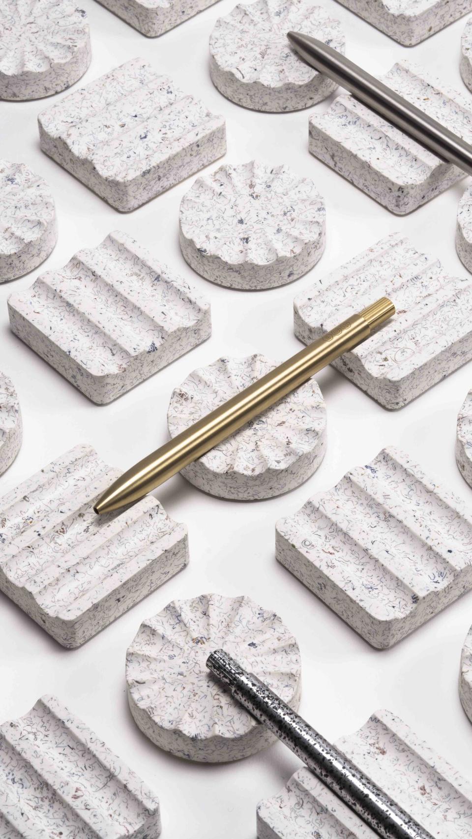 Ebonite terrazzo desk rests by AJOTO paired with sleek metallic pens, showcasing innovative design and craftsmanship.