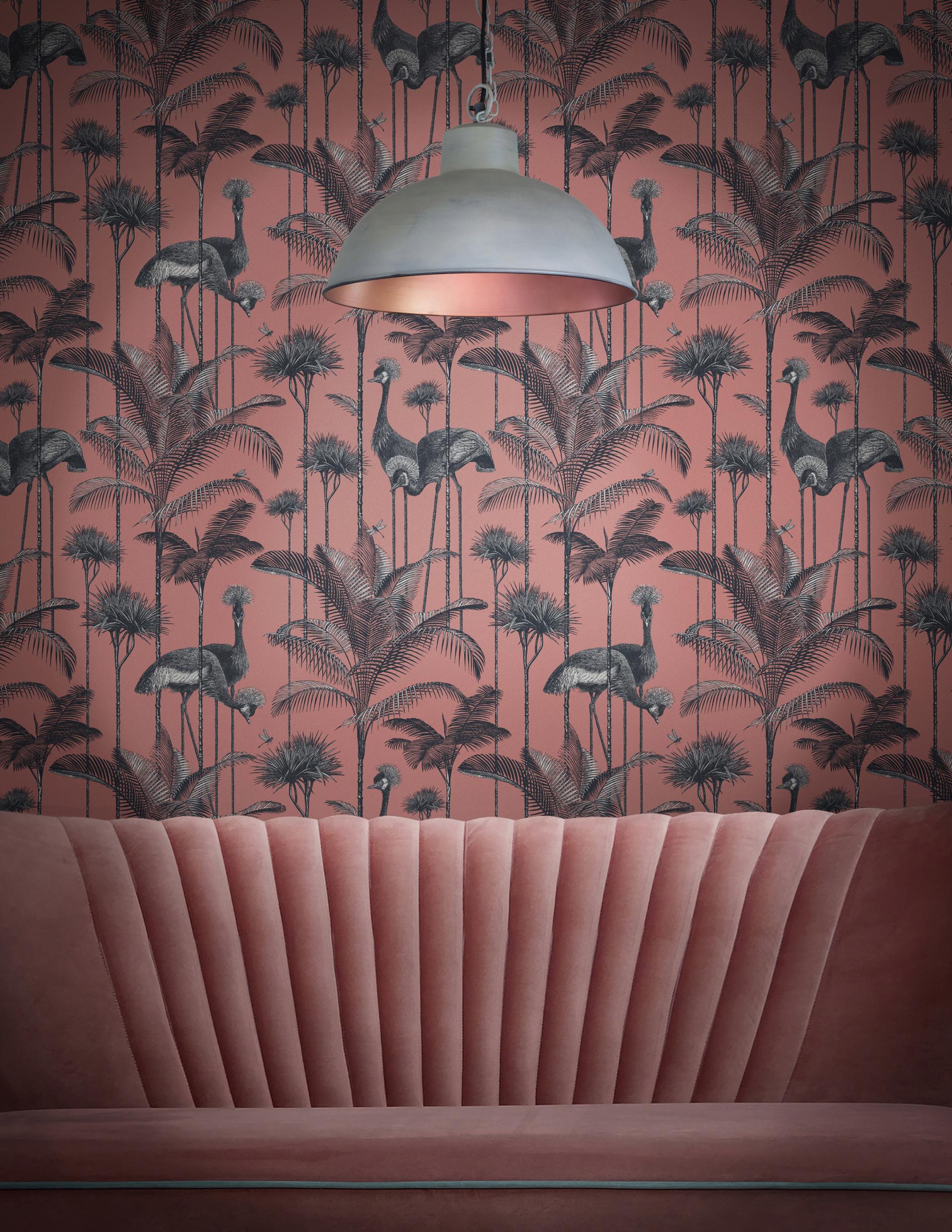 Bold velvet sofa in front of intricate palm tree and flamingo wallpaper, showcasing luxury interior design trends.