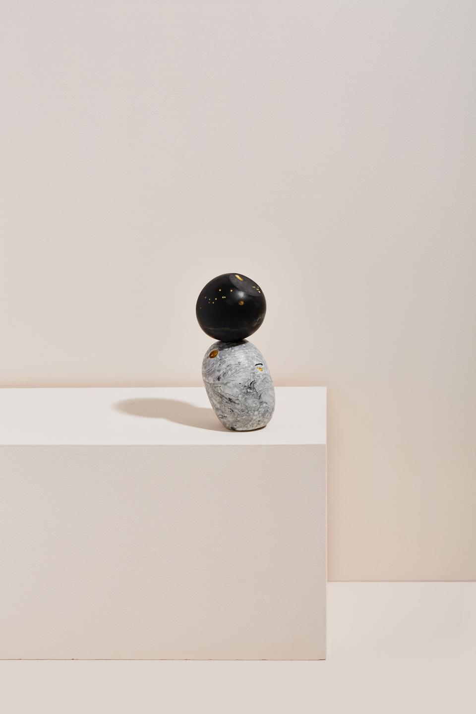 Sculpture by Vic Wright featuring stacked black and gray stones with gold accents, highlighting innovative material use in contemporary art.