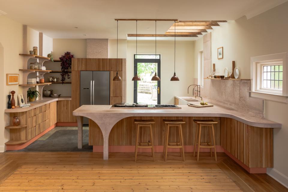 Modern kitchen design featuring poured pink concrete and Scottish Oak cabinetry, showcasing a stylish, curved countertop and warm wood accents.