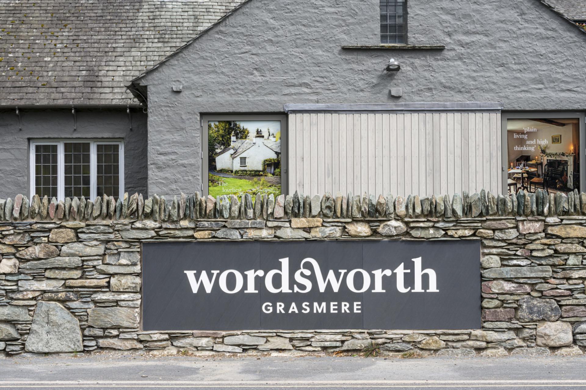 New gallery entrance of The Museum at Wordsworth Grasmere, featuring a stone wall and contemporary signage.
