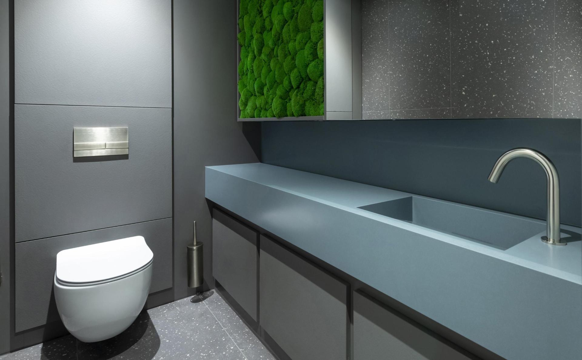 Modern washroom design featuring sleek gray surfaces and a vibrant green moss accent wall, ideal for Instagrammable hospitality spaces.