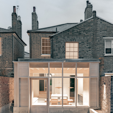 Modern Concrete Plinth House by DGN Studio features a glass façade, creating a seamless indoor-outdoor living space.