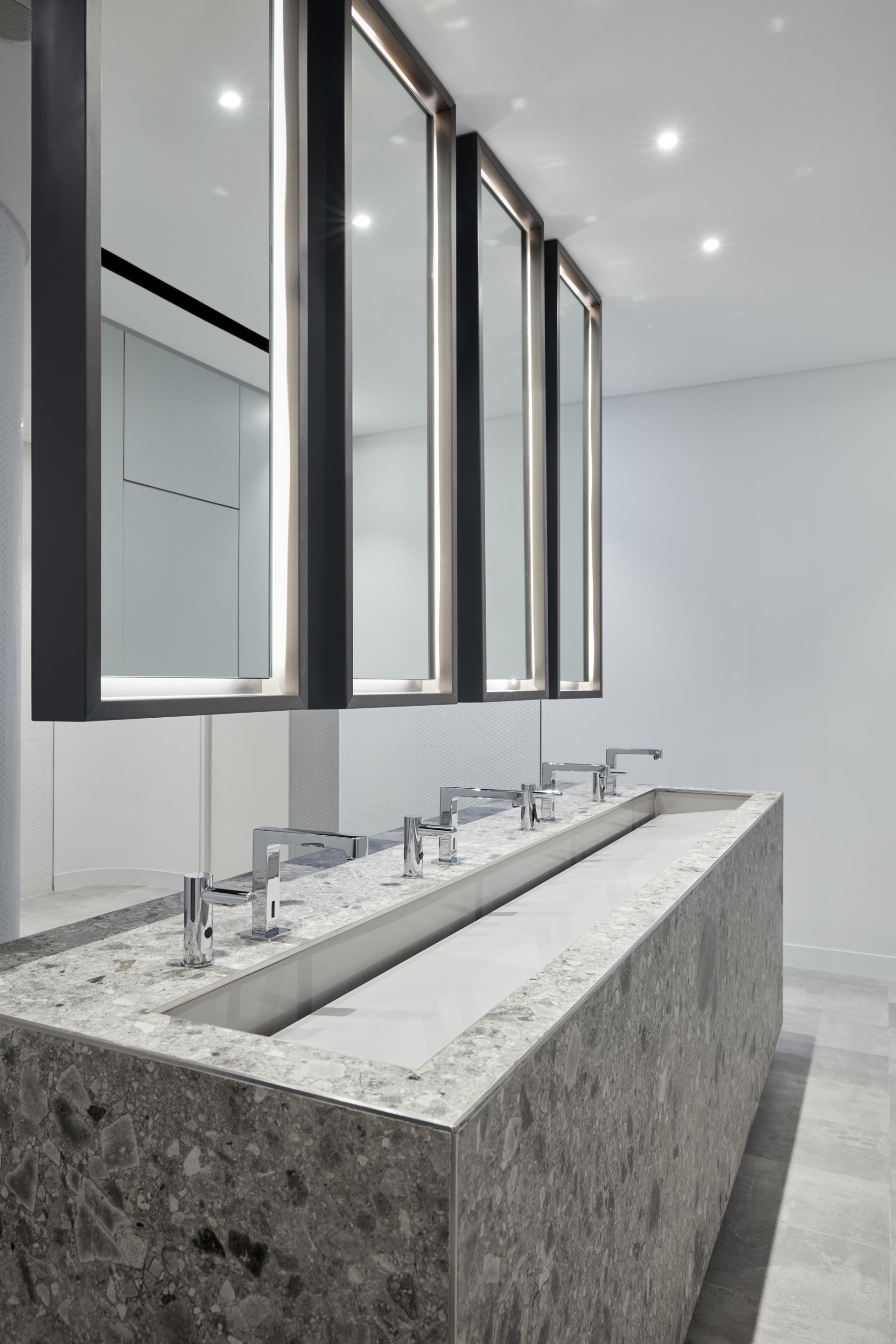 Stylish bathroom sink area featuring modern faucets, illuminated mirrors, and sleek stone countertops at American University of Sharjah.