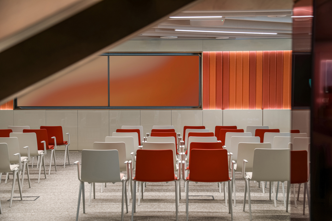 Vibrant meeting room in Dubai featuring colorful chairs and a large screen, embodying nature-inspired design.