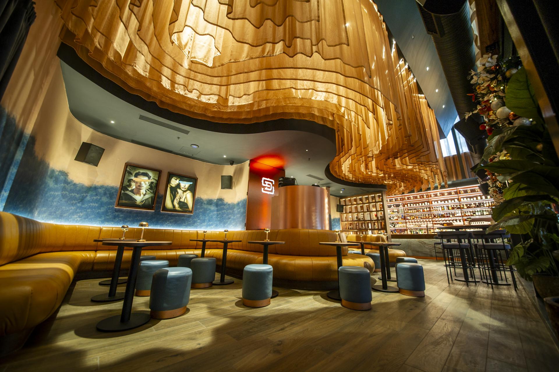 Stylish interior of a contemporary bar featuring artistic lighting, plush seating, and vibrant colors, highlighting innovative design.