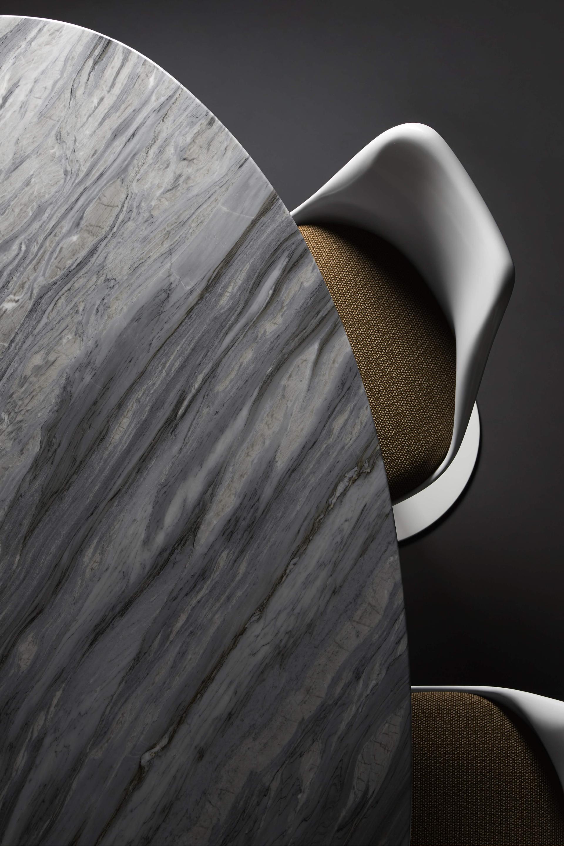 Elegant marble tabletop paired with a modern chair featuring a textured, golden fabric, showcasing contemporary design at the London Design Festival.