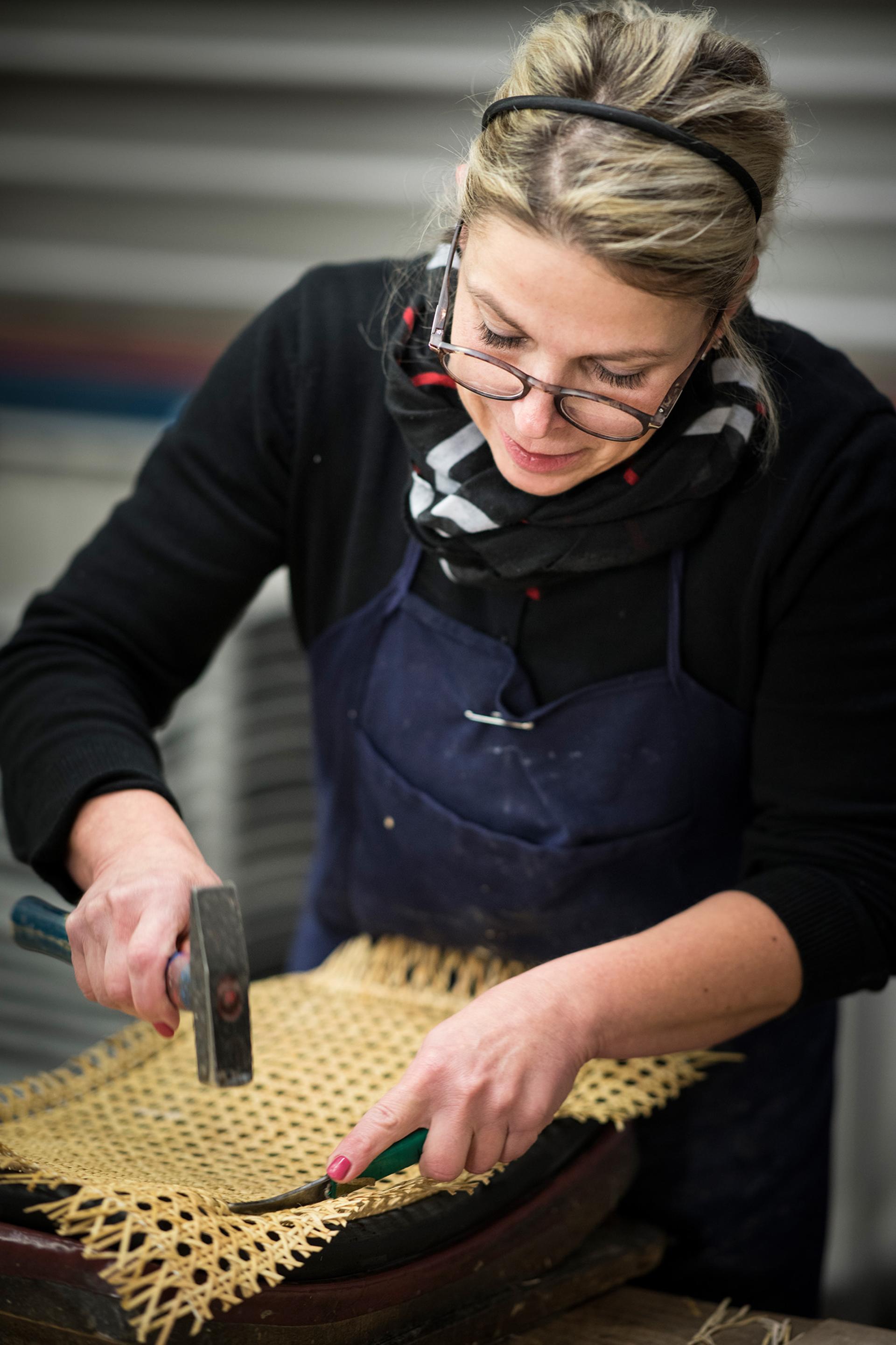Craftsman skillfully weaving rattan material at a production facility, highlighting Thonet's craftsmanship in Germany.