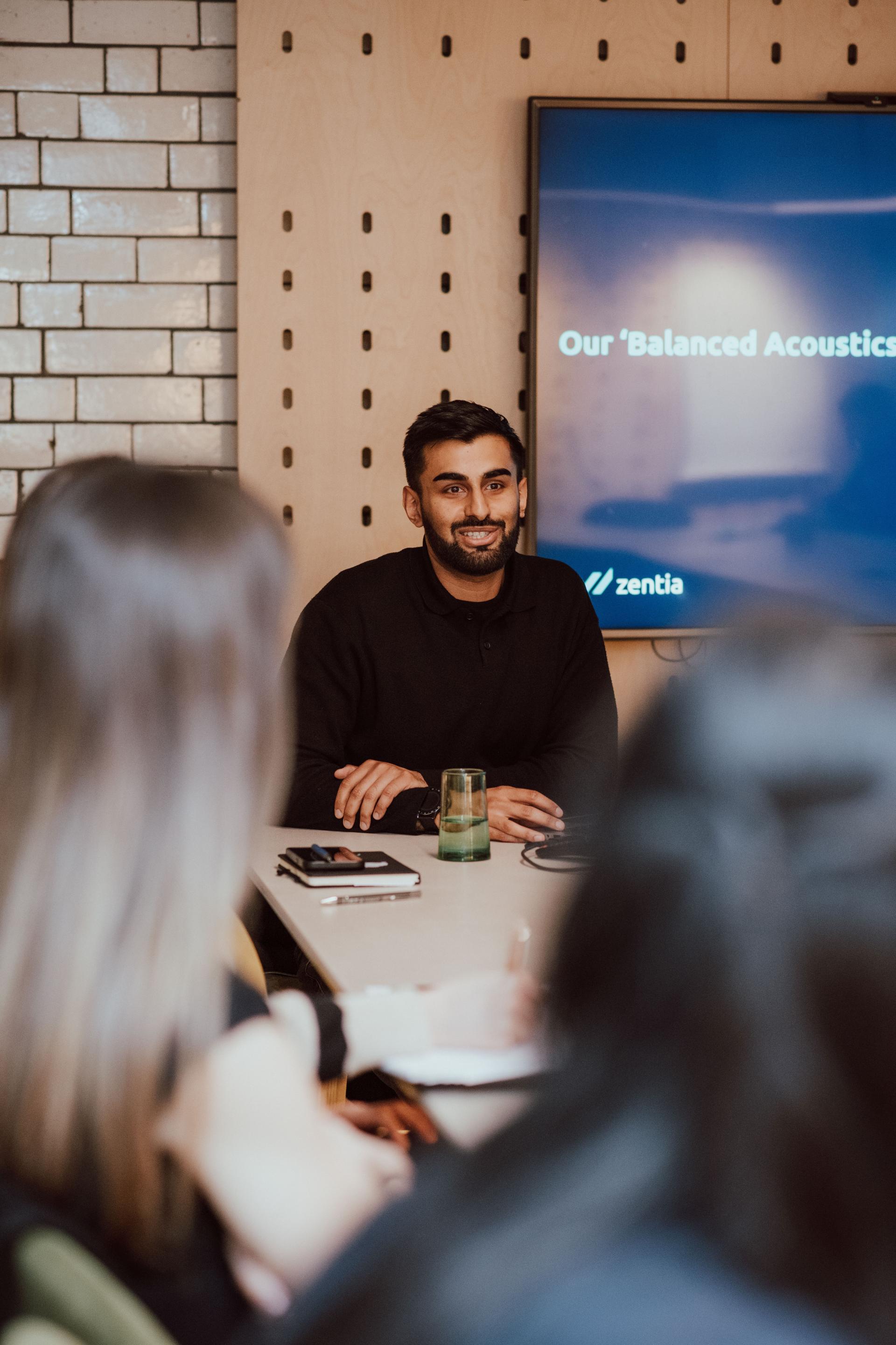 Young professional discussing acoustic design during a creative collaboration session with Manchester Academy students.