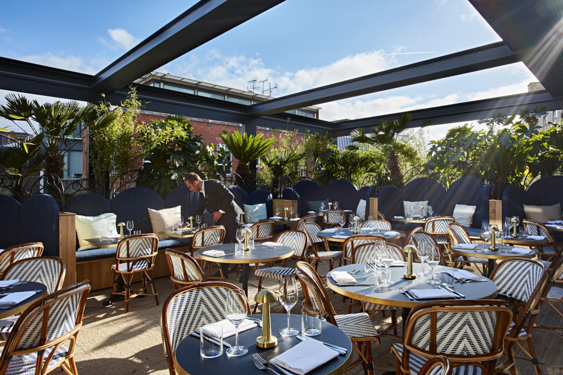 Stylish outdoor dining area featuring Scandinavian design elements and African crafts at The Conduit Members Club.