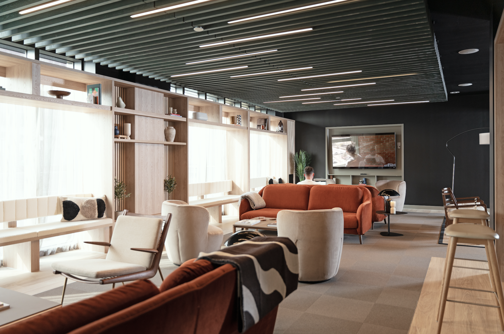 Stylish communal lounge area featuring modern furniture, bright lighting, and a TV, highlighting Vita Group's uhaus brand design.