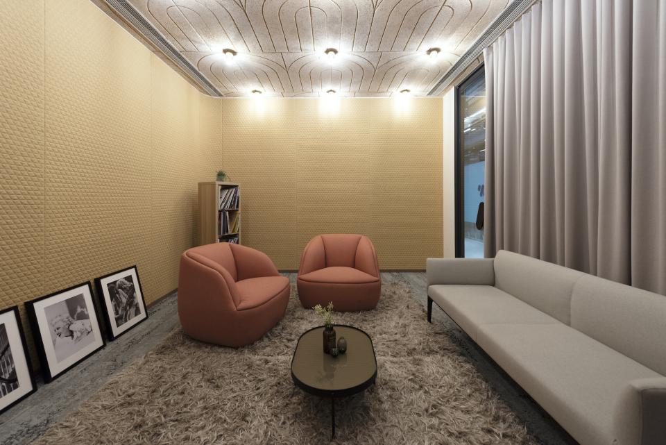 Modern office lounge featuring stylish pink chairs, a minimalist gray sofa, and artistic wall decor in Warner Music Hong Kong's HQ.