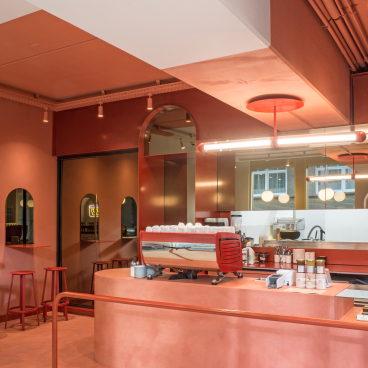 Stylish interior of Buddy Buddy café featuring an artistic red color scheme, barista station, and modern decor elements.