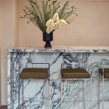 Stylish bar area featuring marble counter, green accents, and elegant floral arrangement in New York nail studio, Paintbox.