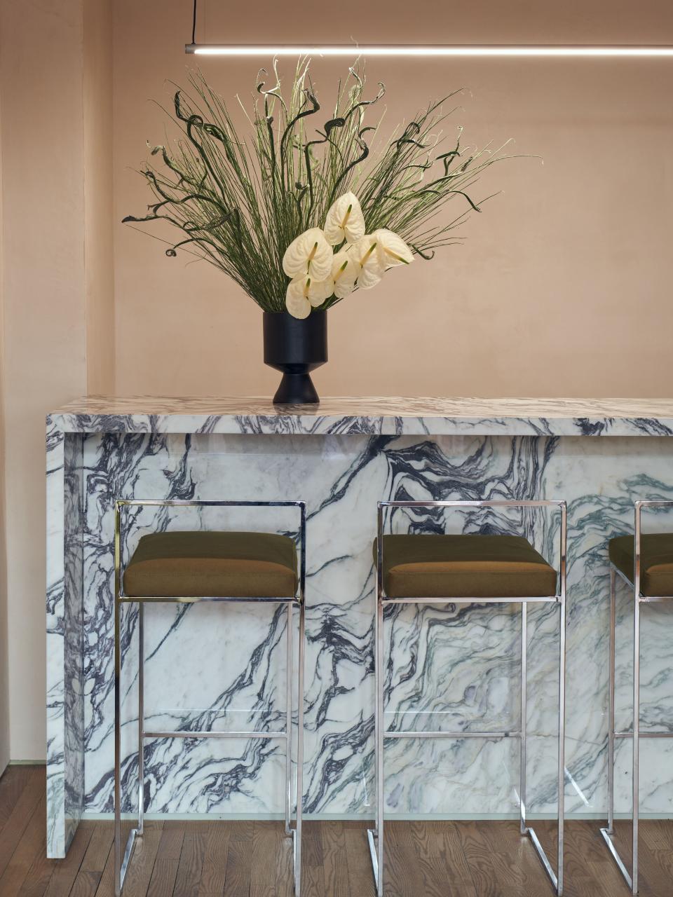 Stylish bar area featuring marble counter, green accents, and elegant floral arrangement in New York nail studio, Paintbox.