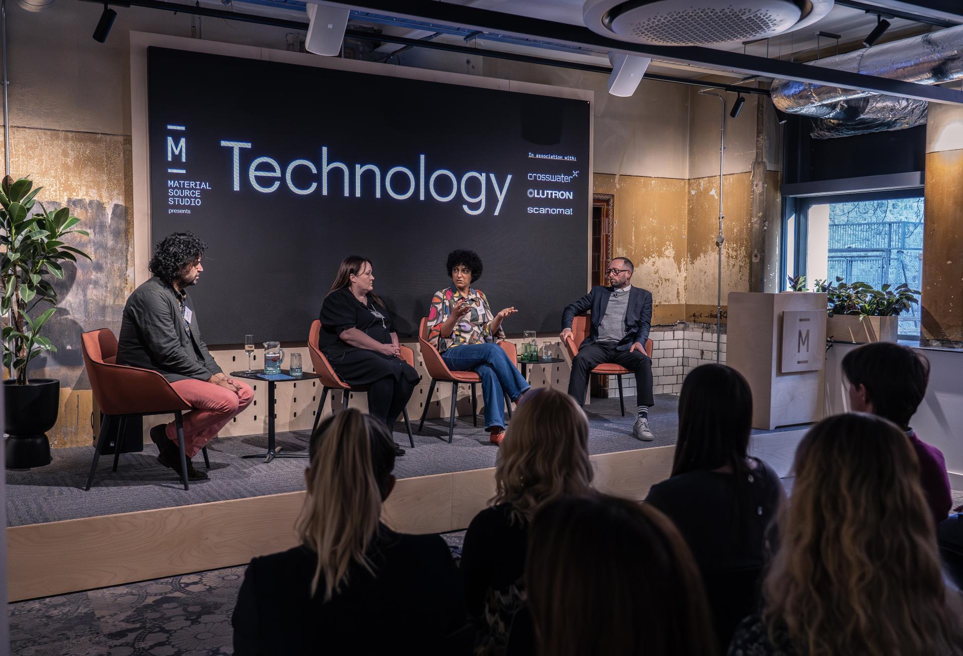 Panel discussion on technology featuring four speakers at Material Source Studio event, with a large screen in the background.