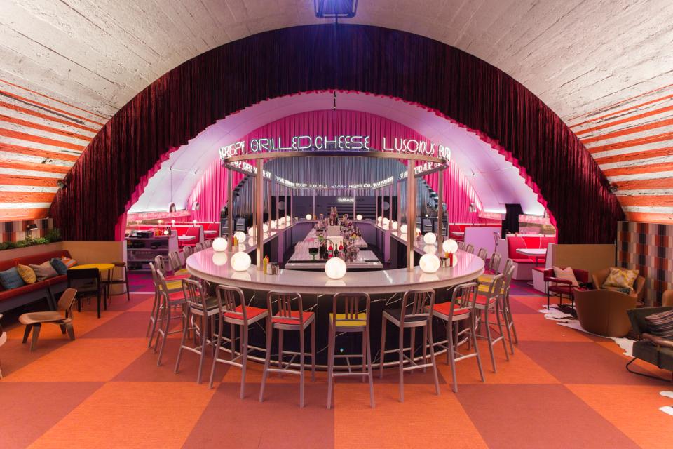 Vibrant interior of a modern bar featuring colorful seating, a circular counter, and dynamic lighting design.