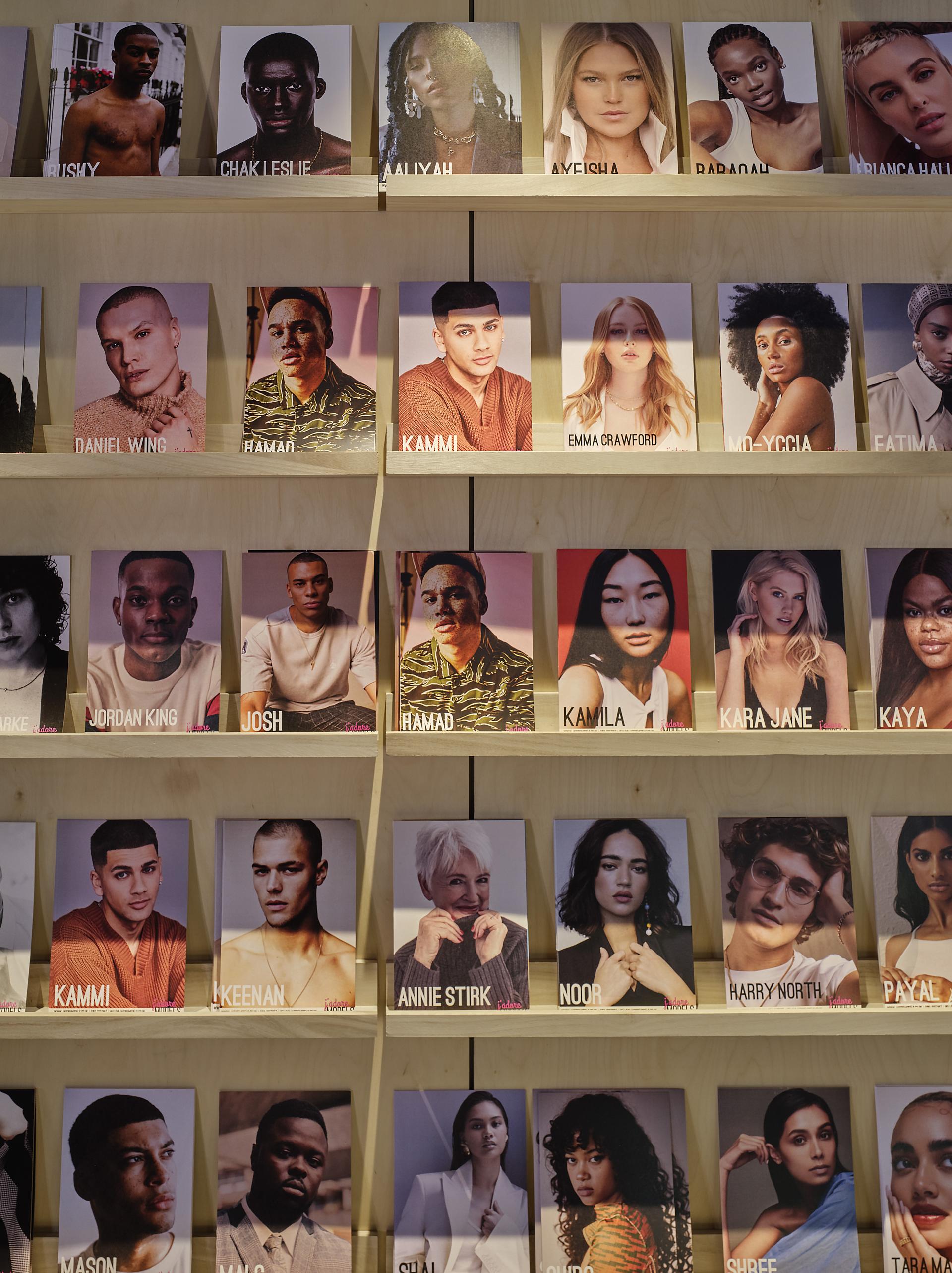 Model cards displayed on wooden shelves at J’adore Models HQ, showcasing diverse talent managed by Workshop Design Studio.