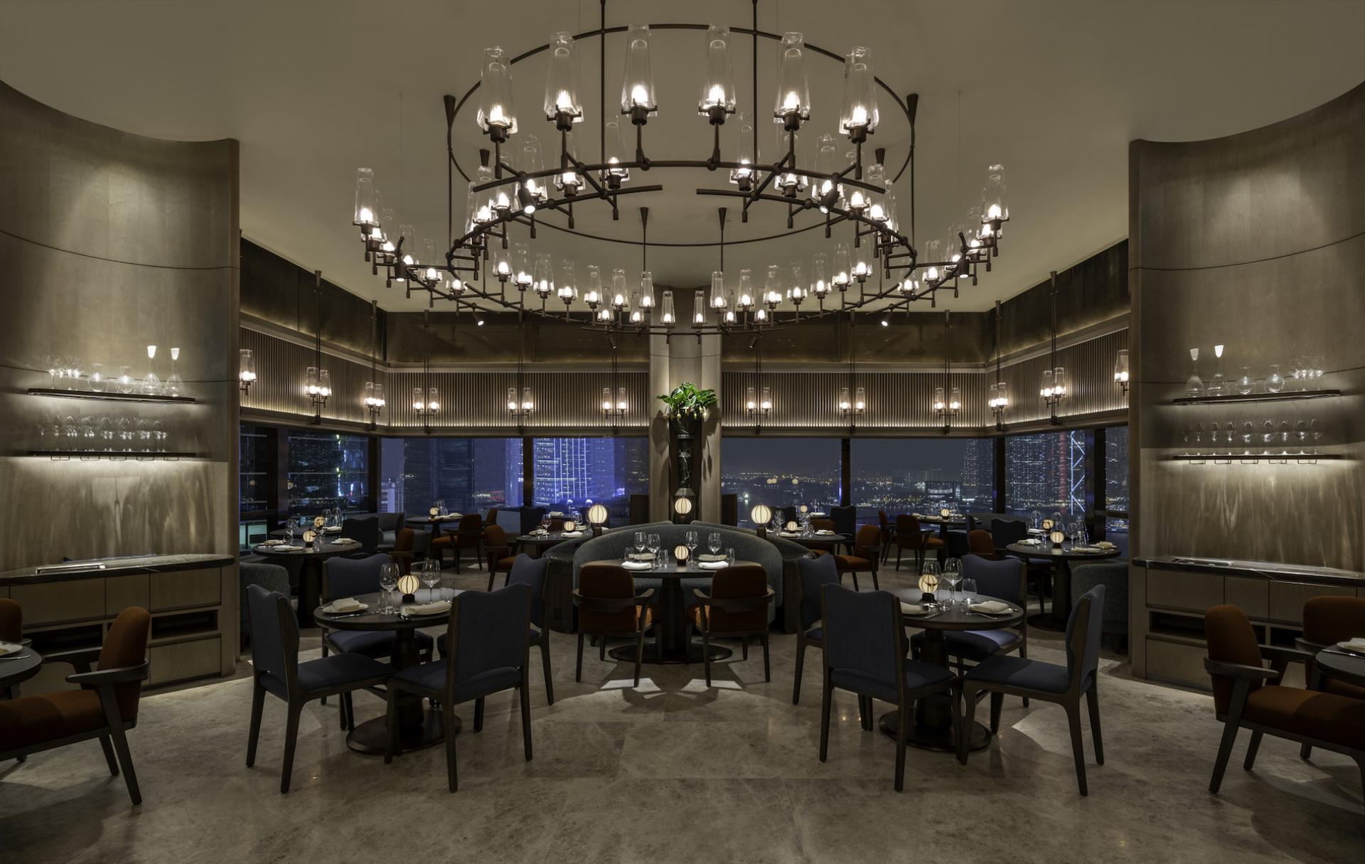 Elegant dining area of The Upper House in Hong Kong, featuring Art Deco design, stunning chandelier, and city skyline view.