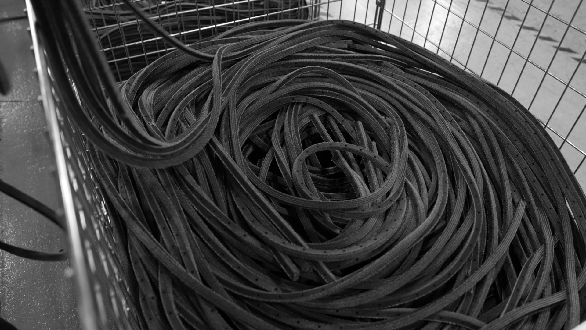 Black rubber strips coiled in a metal basket, showcasing materials used in sustainable flooring production at Forbo.