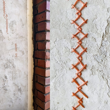 Artisan wall finish featuring unique, textured patterns and contrasting orange thread, showcasing Vacarda Design's modern craftsmanship.