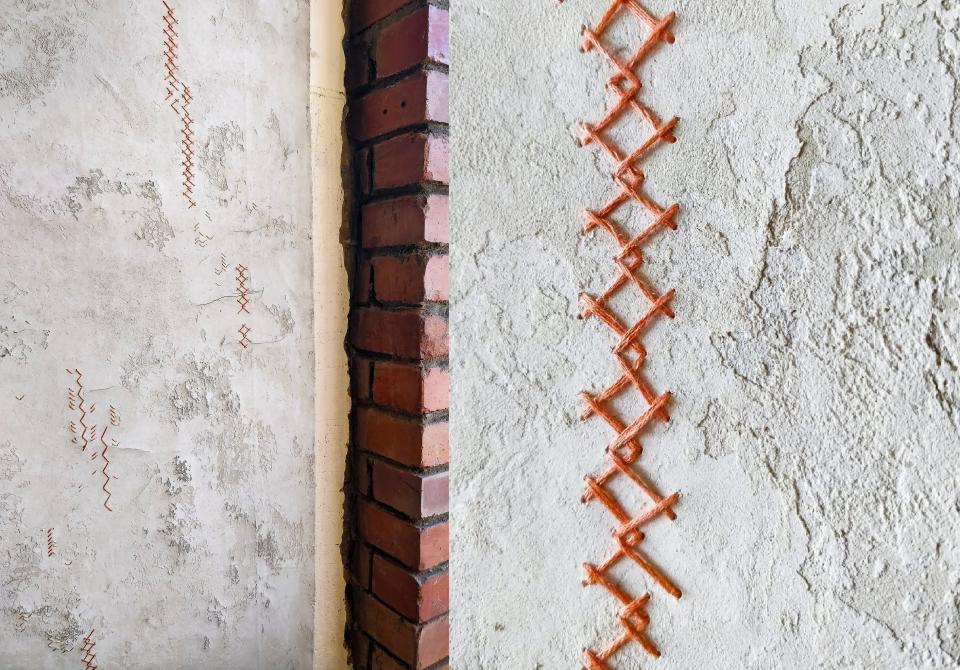 Artisan wall finish featuring unique, textured patterns and contrasting orange thread, showcasing Vacarda Design's modern craftsmanship.