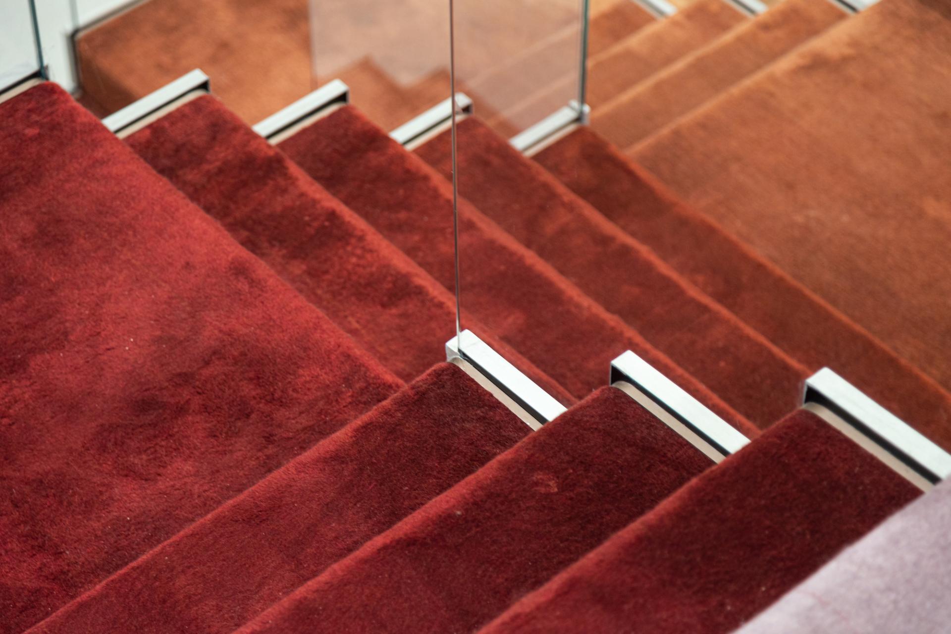 Luxurious crimson stair carpet leading to the Jaipur Rugs showroom, showcasing Rajasthani architectural design elements.