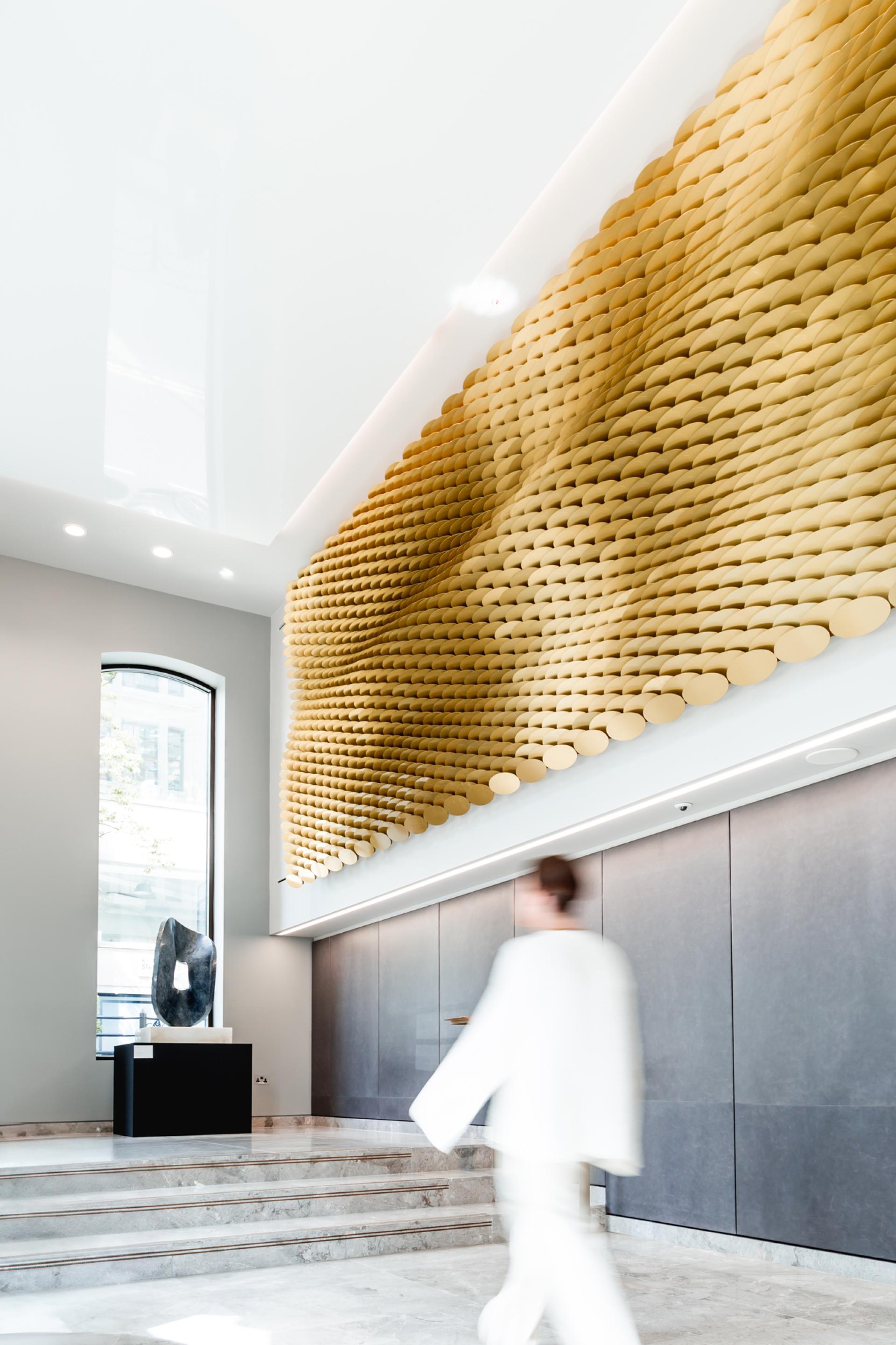 Elegant interior featuring a sculptural golden wall installation, highlighting innovative materiality and design by Giles Miller Studio.