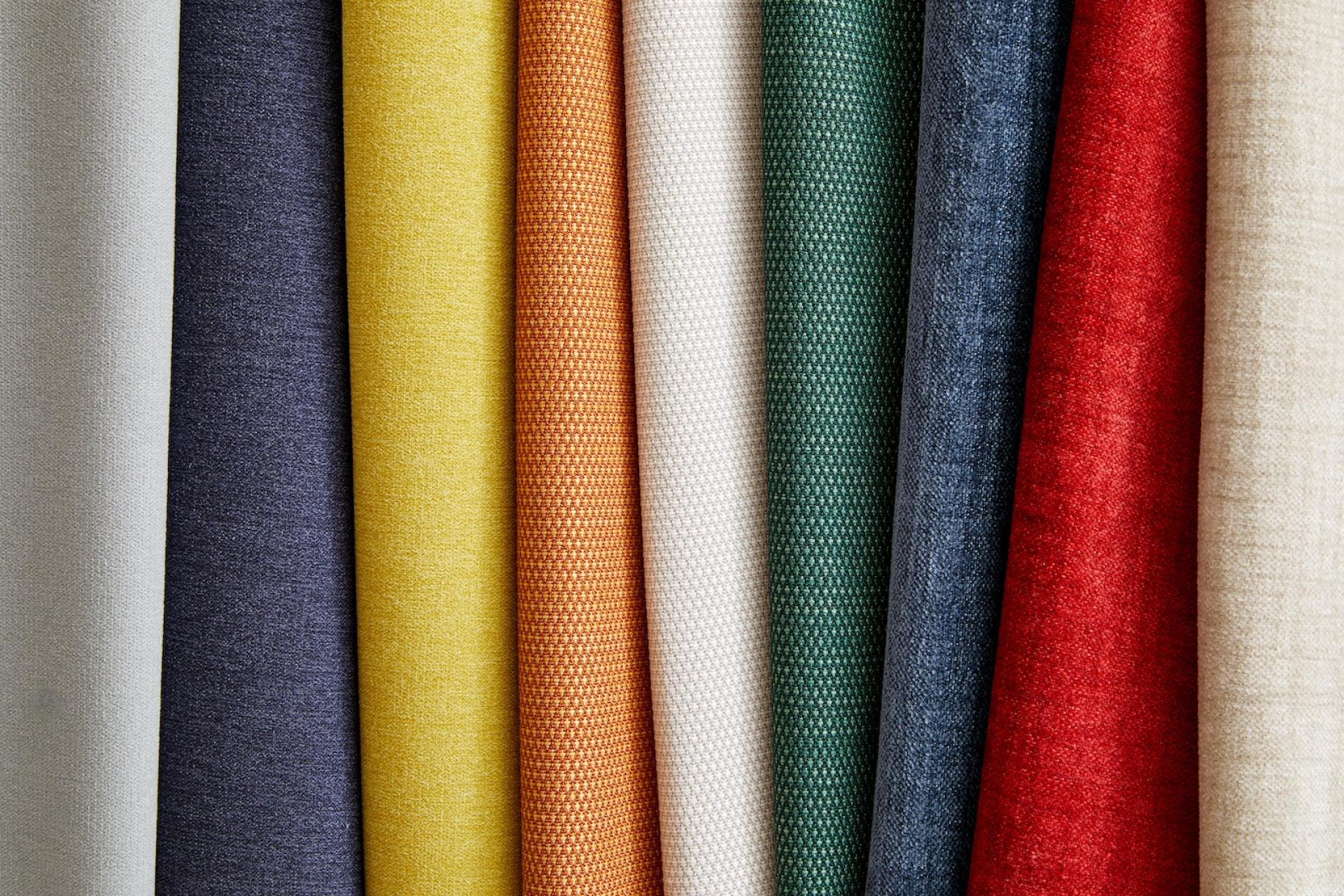 Colorful Supreen performance upholstery fabrics arranged in a row, showcasing various textures and patterns ideal for durable furniture.