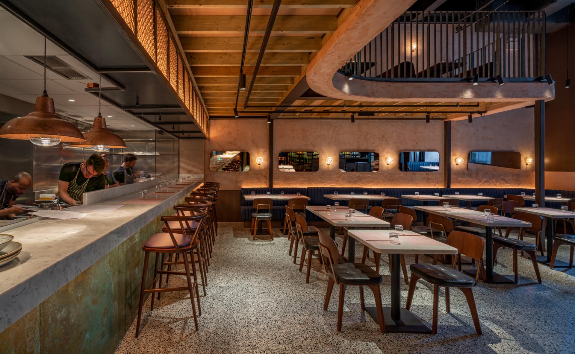 Elegant interior of Chef Andrew Wong's restaurant featuring a marble bar, wooden accents, and stylish seating at Bloomberg Arcade.
