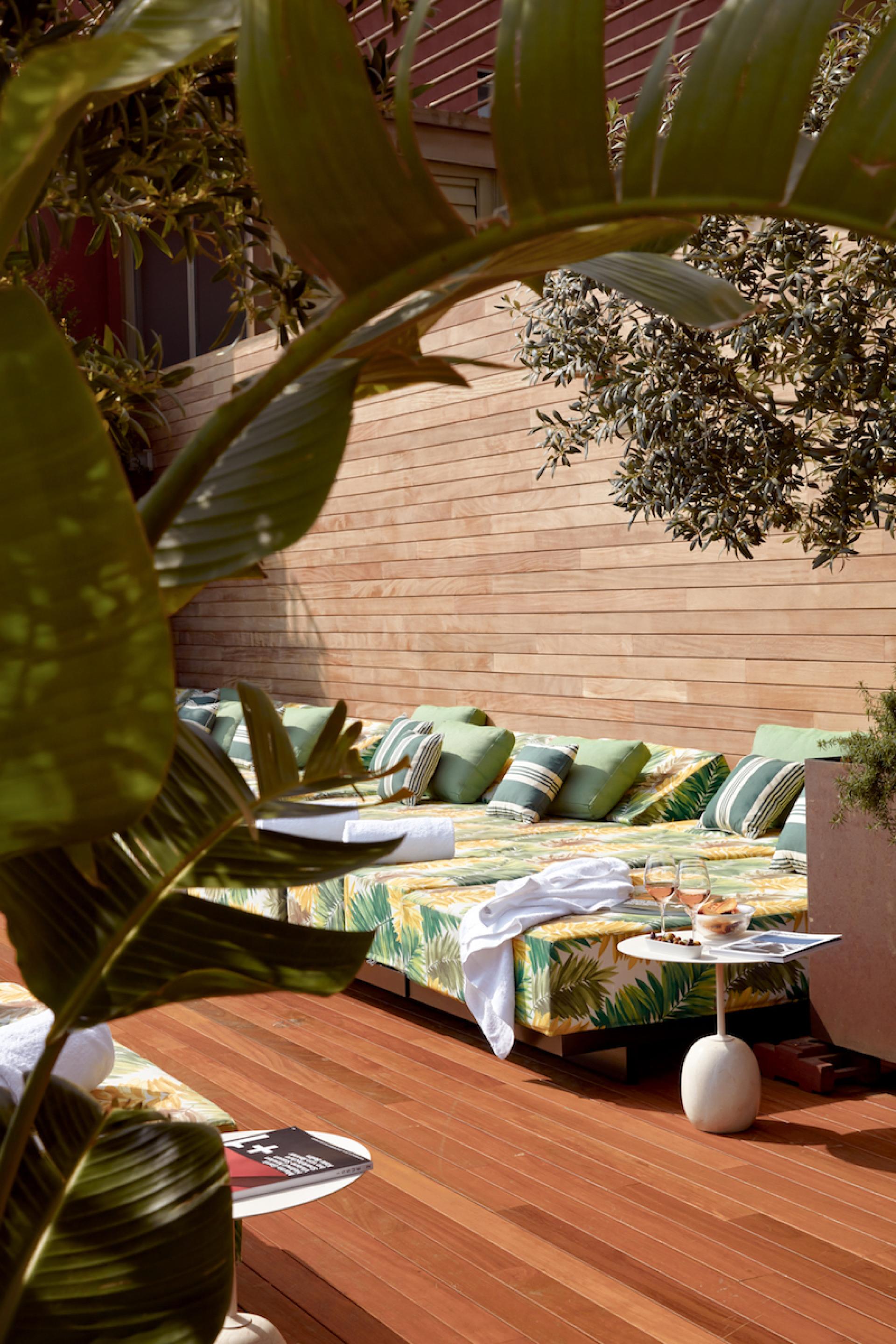 Vibrant lounging area with tropical decor, showcasing Sir Victor hotel's relaxing outdoor space in sunny Barcelona.