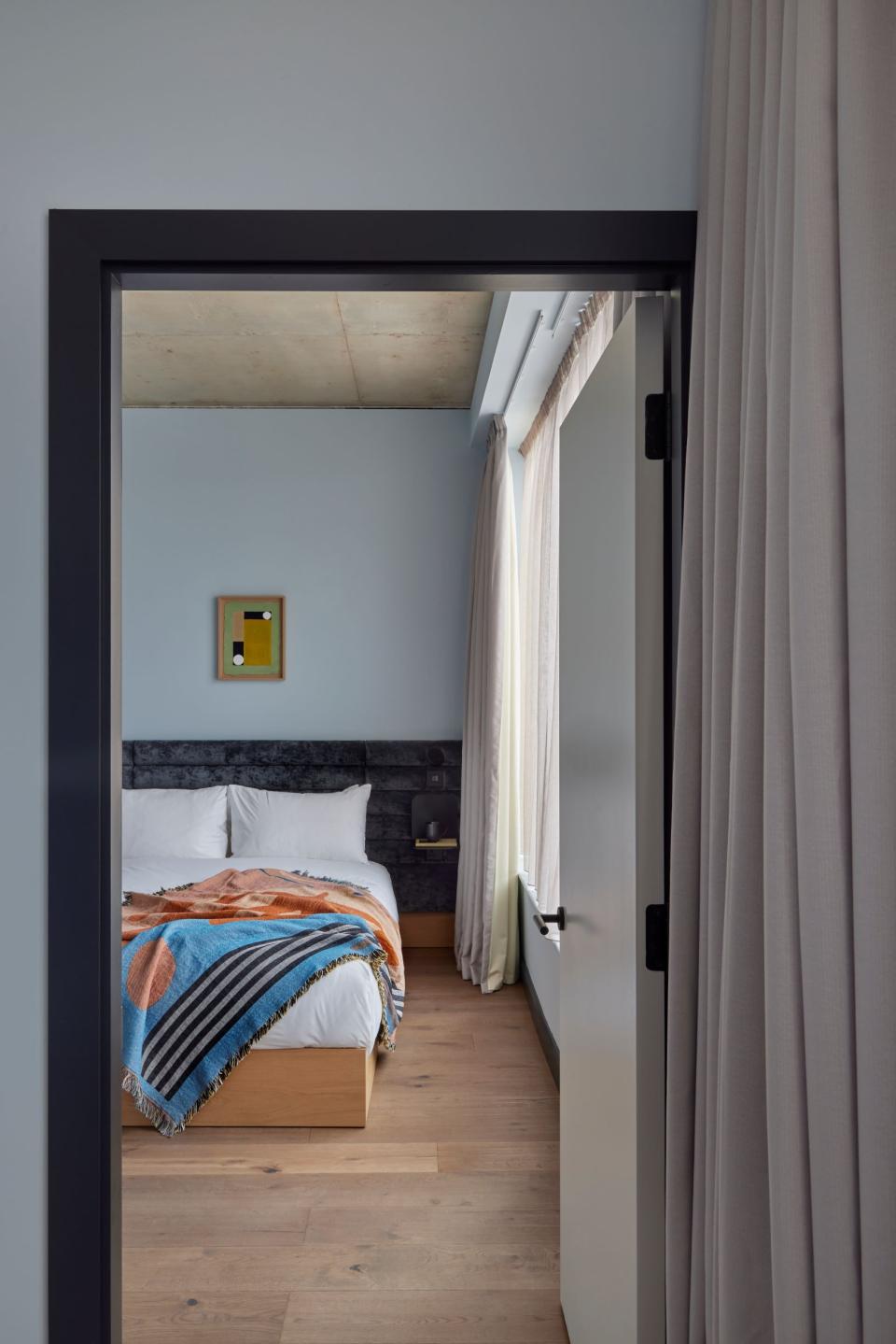 Stylish bedroom at Beckett Locke aparthotel featuring a cozy bed, decorative blanket, and natural light.